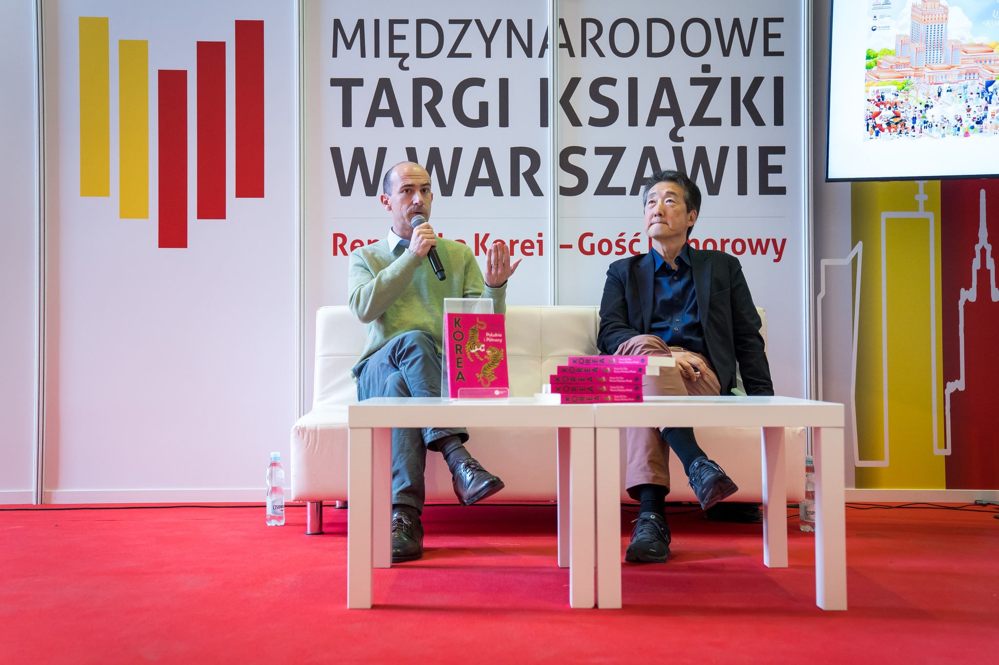 Panel dyskusyjny podczas Międzynarodowych Targów Książki w Warszawie, autorzy rozmawiają na scenie przed publicznością.