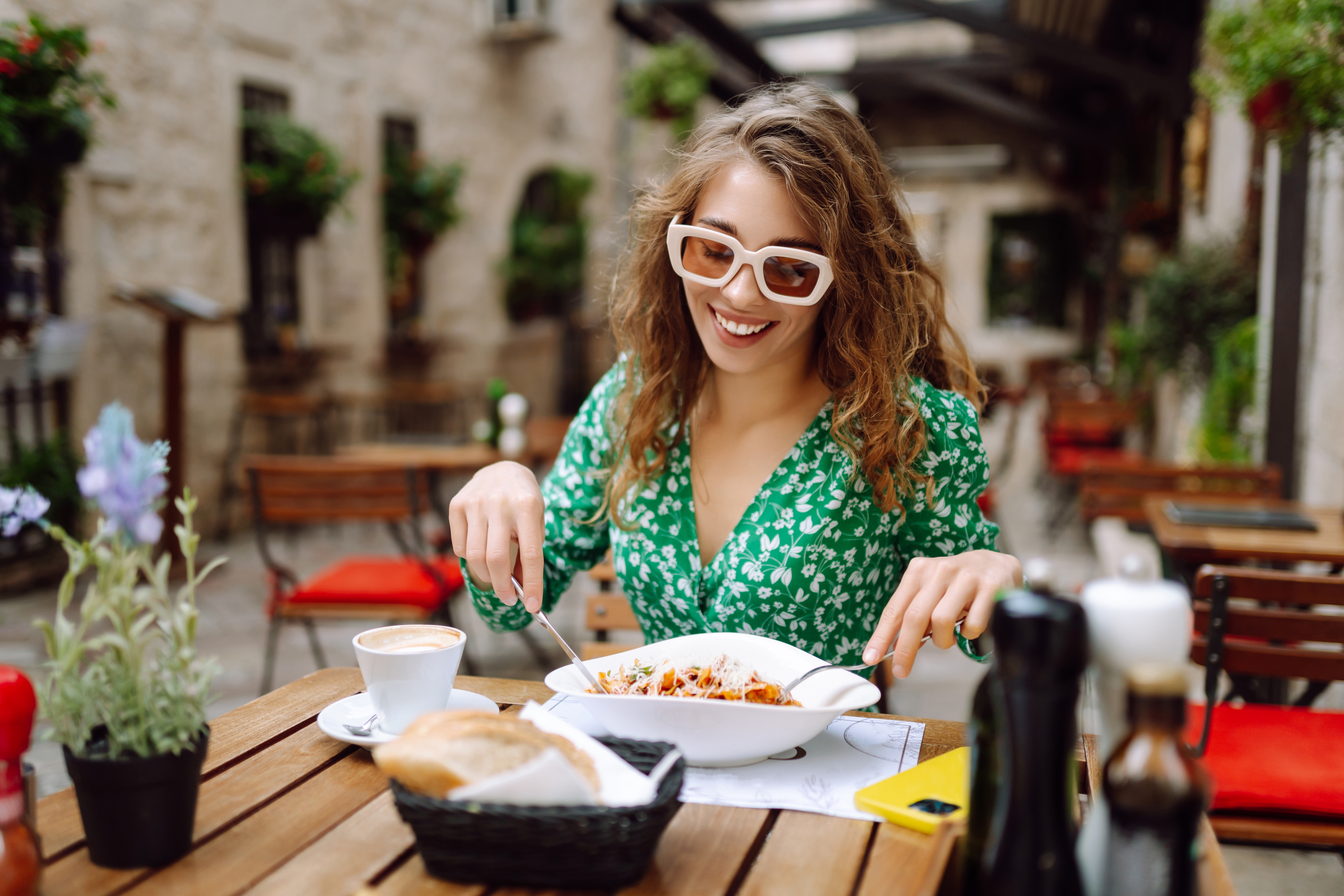 Kobieta siedzi przy stoliku w restauracyjnym ogródku i je makaron podczas kulinarnej podróży po Europie.