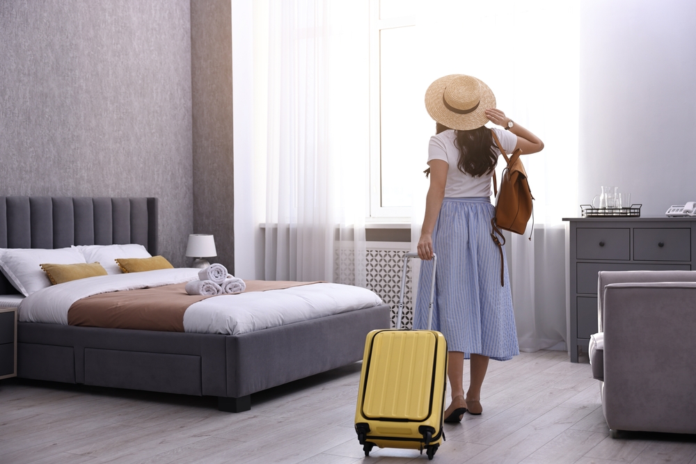 Kobieta z walizką w pokoju hotelowym podczas wakacyjnego wyjazdu