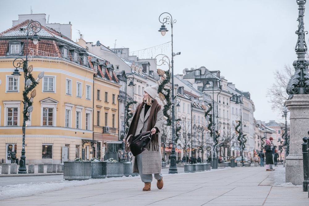 Kobieta idąca zimą ulicą Starego Miasta w Warszawie, kamienice w tle, chłodny poranek.