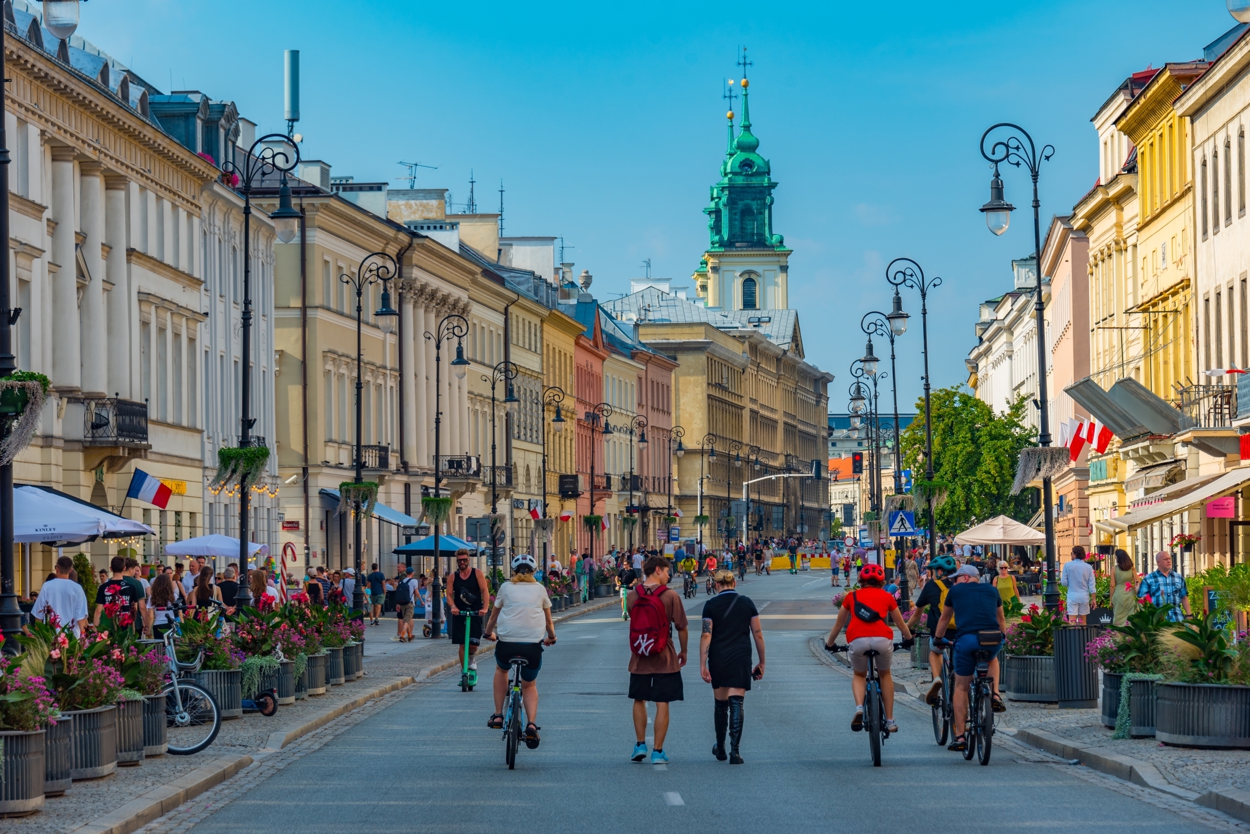 Wiosenne centrum Warszawy, spacerowicze i rowerzyści na jednej z ulic w weekend.