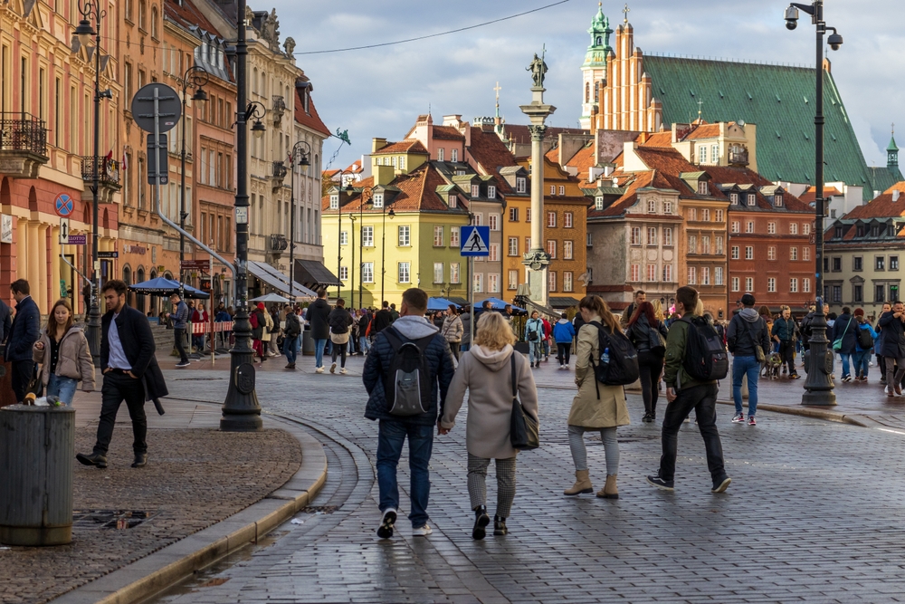 pacerowicze na Starym Mieście w Warszawie, w tle kolorowe kamienice i kościół św. Anny