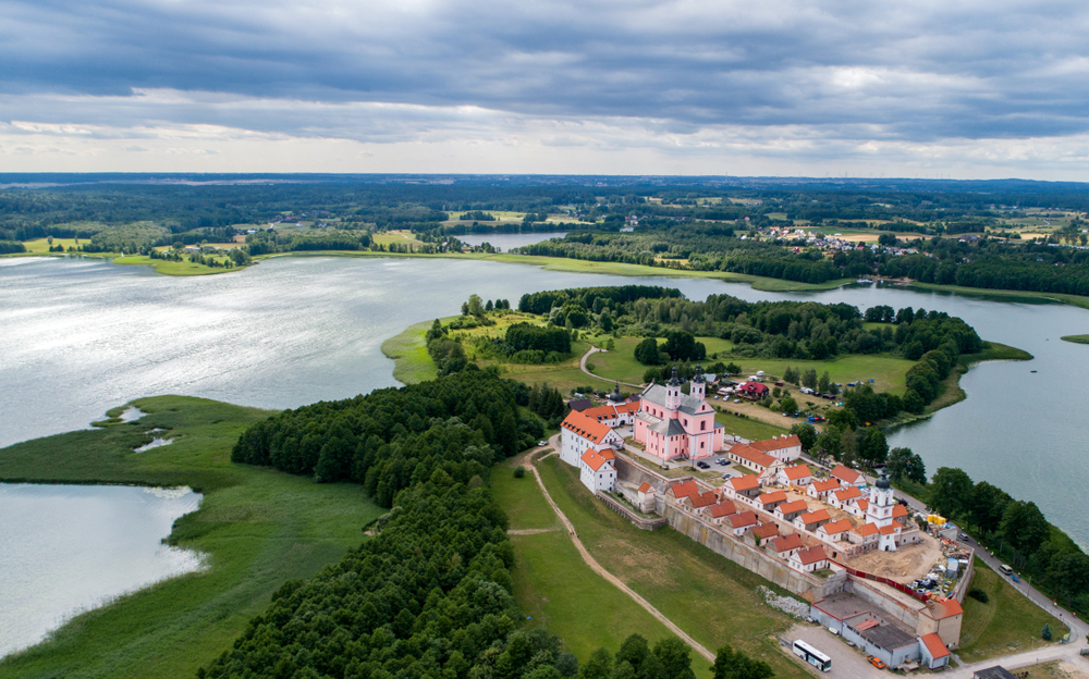 Widok z lotu ptaka na Pokamedulski Zespół Klasztorny w Wigrach, położony na półwyspie otoczonym wodami jeziora Wigry i zielenią.