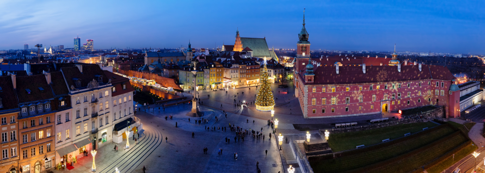 Panorama Placu Zamkowego i Starego Miasta w Warszawie o zmierzchu, z Zamkiem Królewskim, kolumną Zygmunta i oświetlonymi kamienicami zimą.