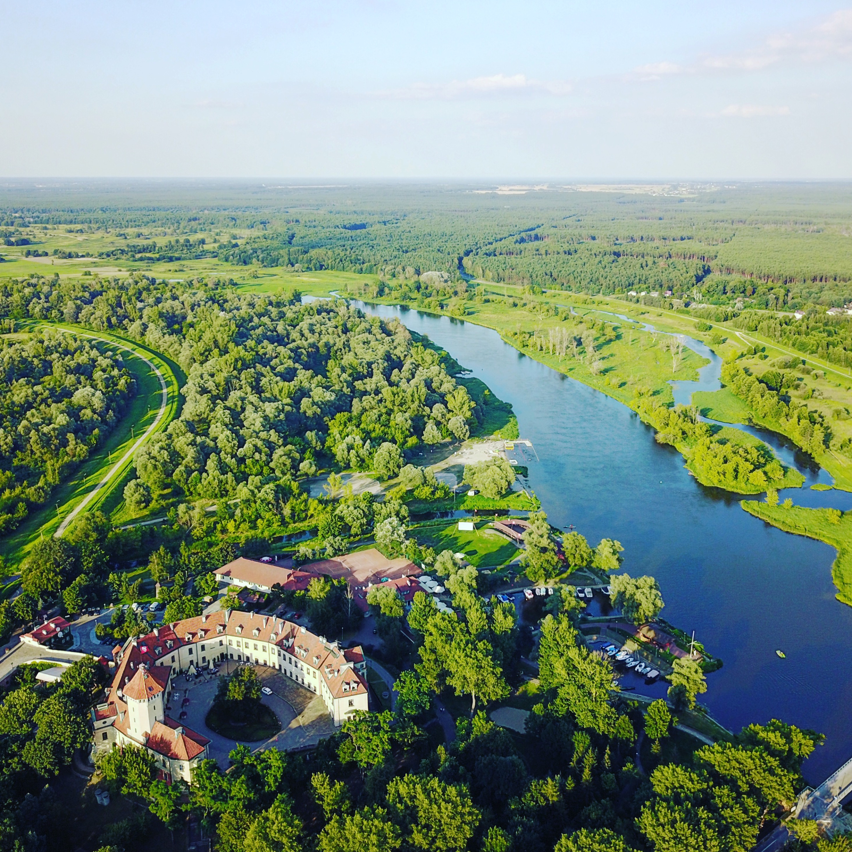 Widok z lotu ptaka na zamek w Pułtusku i zakole Narwi otoczone zielenią.